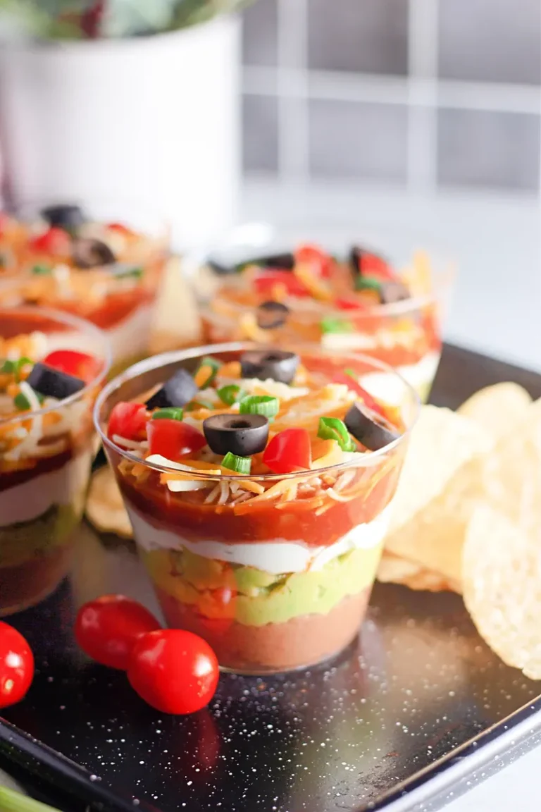 Beautiful 7 layer dip cups with colorful toppings served with tortilla chips