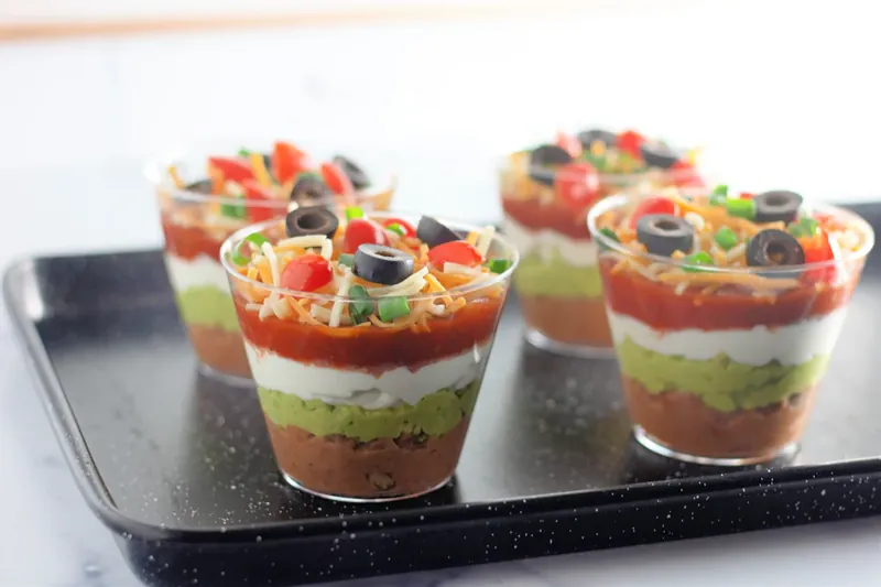 Completed 7 layer dip cups with all toppings on serving tray