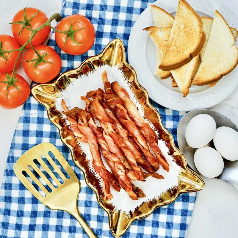 Crispy bacon twists served on gold plate with toast and eggs