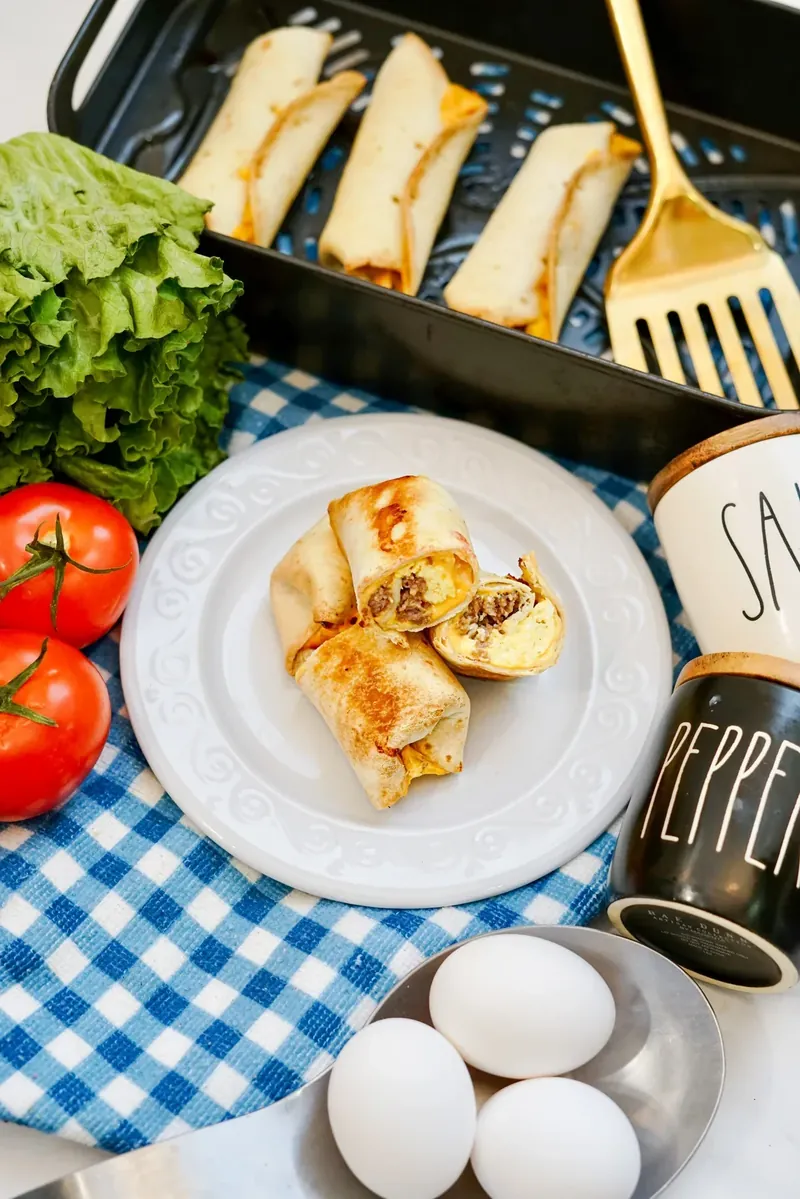 Complete breakfast burrito meal setup with air fryer basket and plated burritos