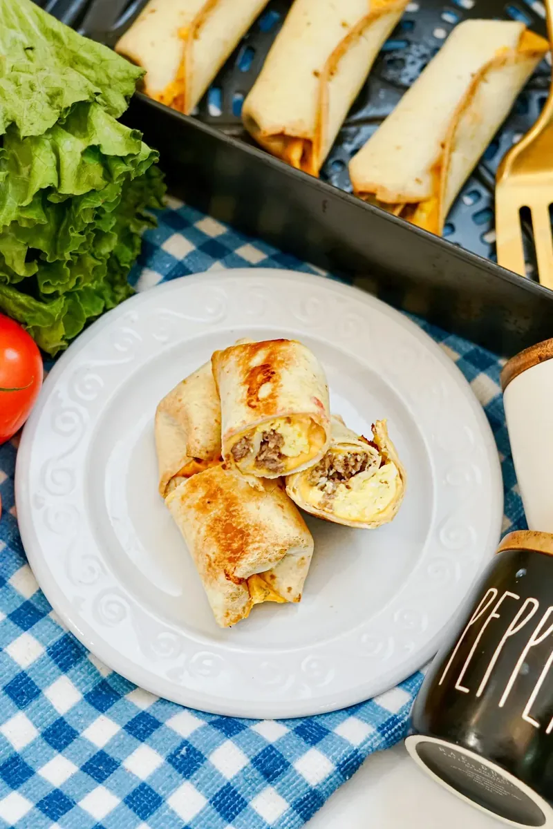 Freshly cooked breakfast burritos in air fryer basket with golden brown exterior