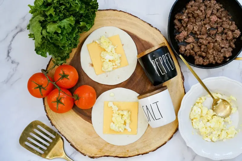 Scrambled eggs being added to tortillas with cheese