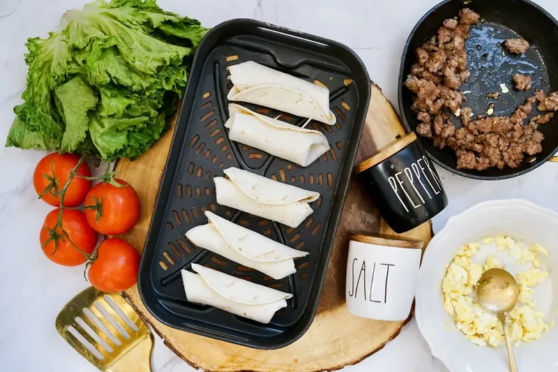 Breakfast burritos rolled up and secured with toothpicks in air fryer basket