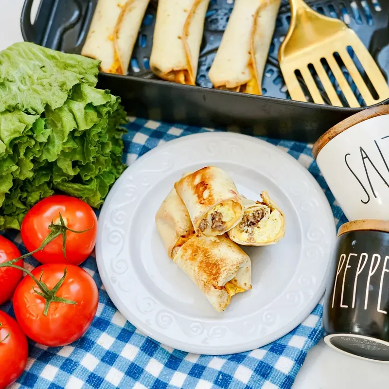 Golden brown breakfast burritos cooking in air fryer basket