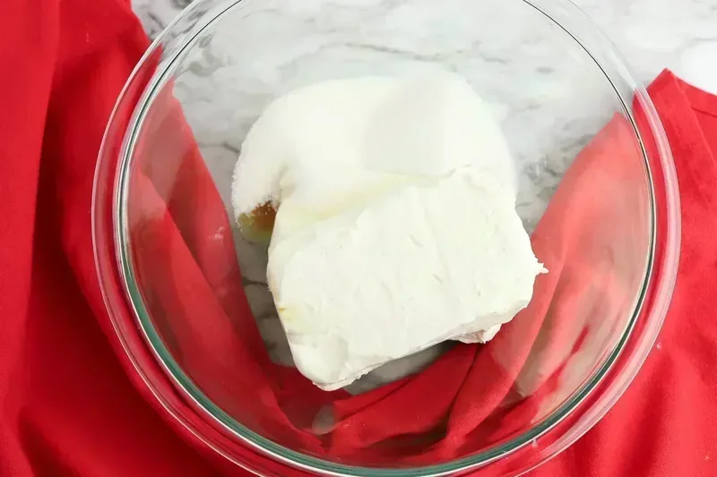 Softened cream cheese blocks in a glass mixing bowl