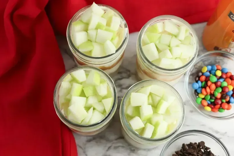 Freshly diced green Granny Smith apples on top of chilled cheesecake jars