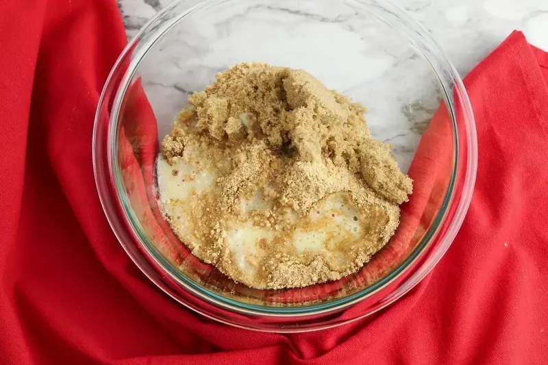 Graham cracker crumb mixture with brown sugar and melted butter in a glass bowl