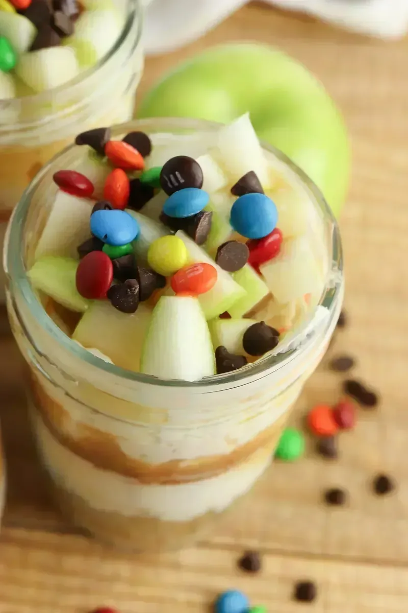 Close-up of single candy apple cheesecake jar showing detailed layers and colorful candy toppings