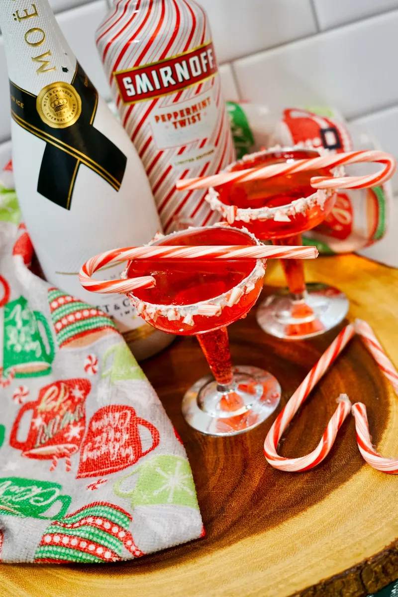 Elegant candy cane mimosa cocktail with champagne bottle and holiday decorations