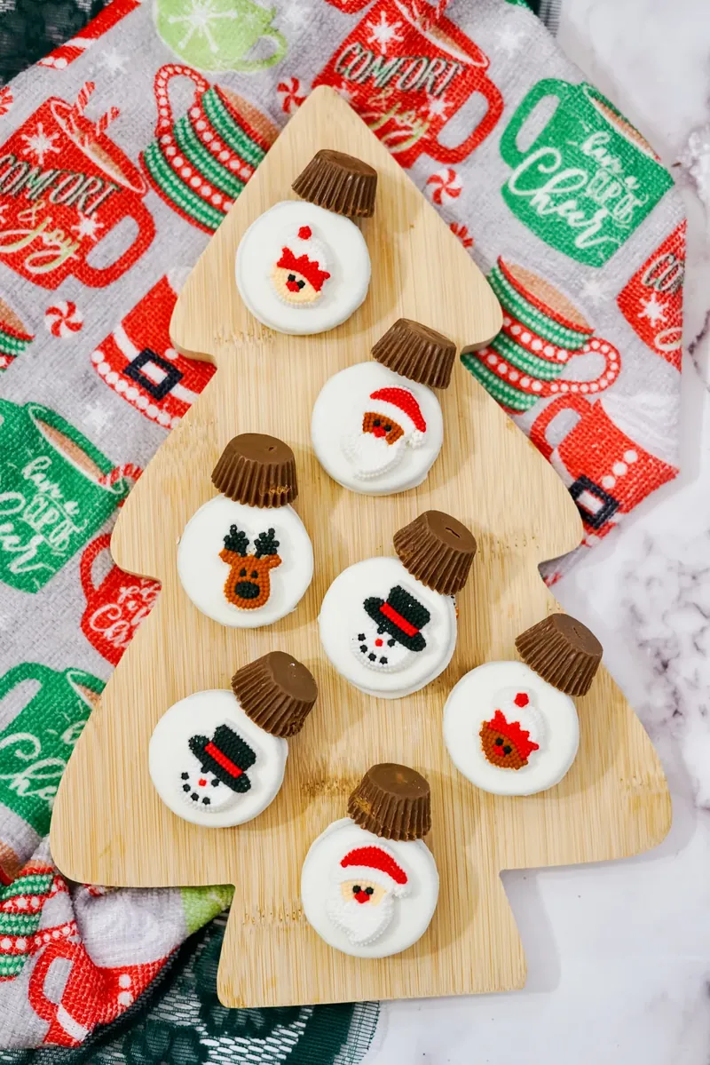 Christmas ornament Oreos arranged on wooden Christmas tree serving board with holiday towels