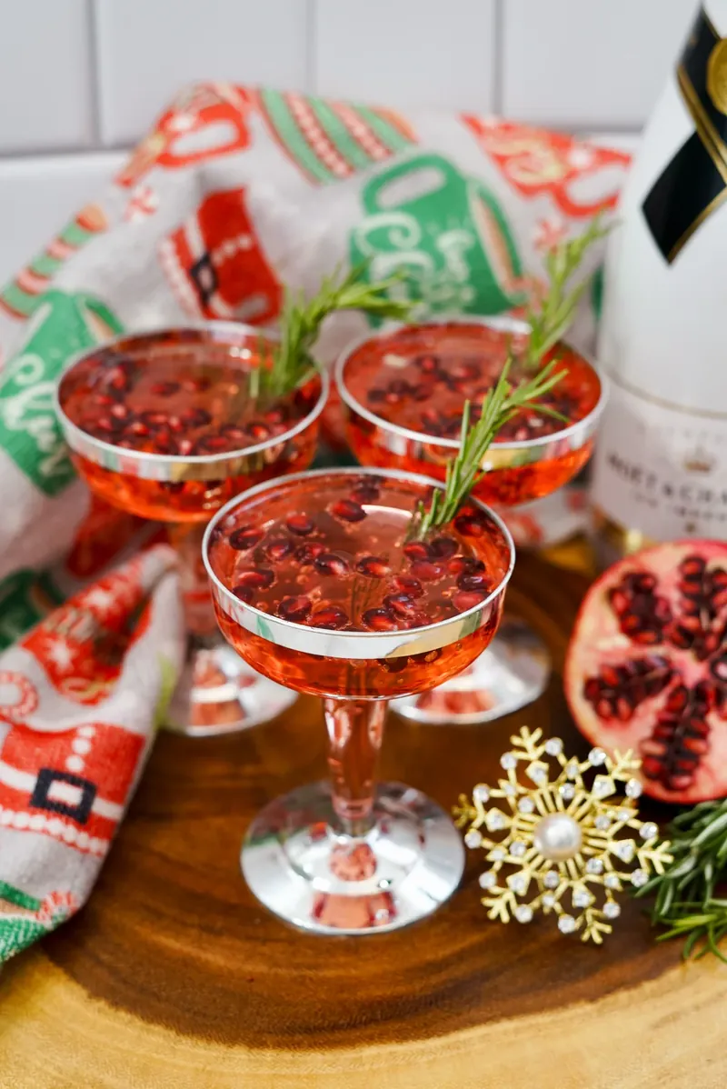 Close up of Christmas pomegranate mimosas with festive garnishes and holiday decorations