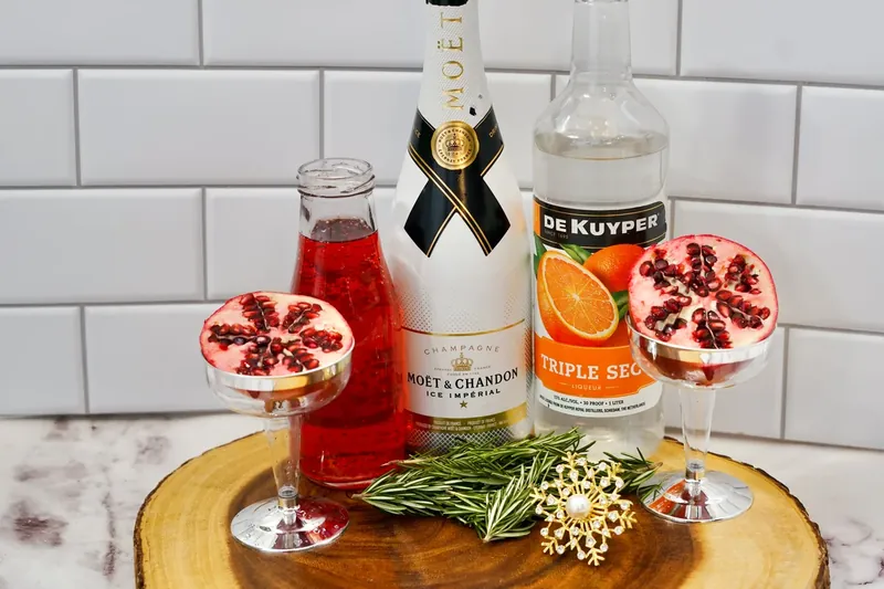 Ingredients for Christmas pomegranate mimosa including champagne, pomegranate juice, orange liqueur, and fresh pomegranate