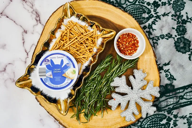 Ingredients for Christmas tree cheese appetizer including pretzel sticks, cheese wedges, rosemary and red pepper flakes