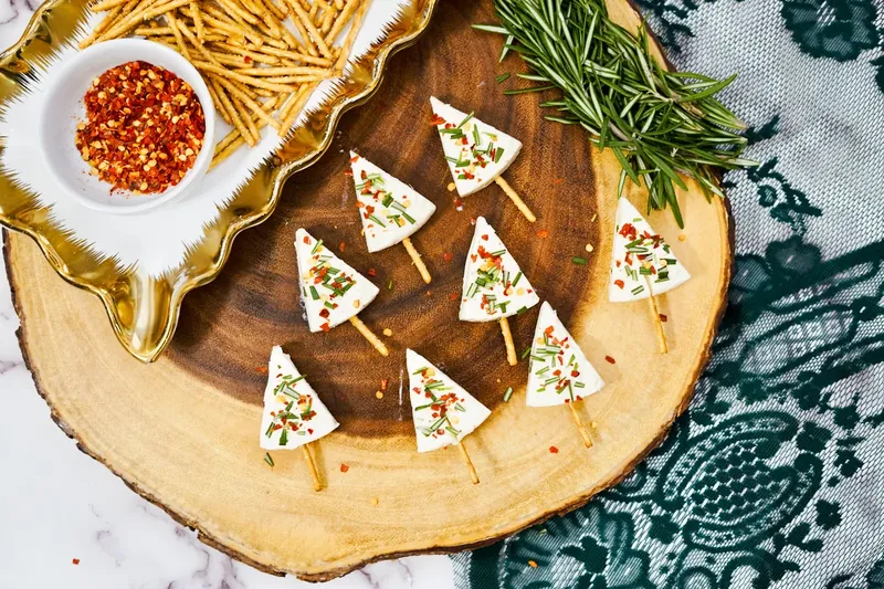Completed Christmas tree cheese appetizers decorated with rosemary and red pepper flakes