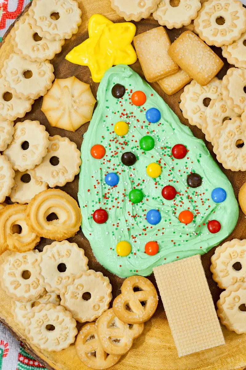 Finished Christmas tree frosting board with decorated green tree and surrounding cookies on wooden board