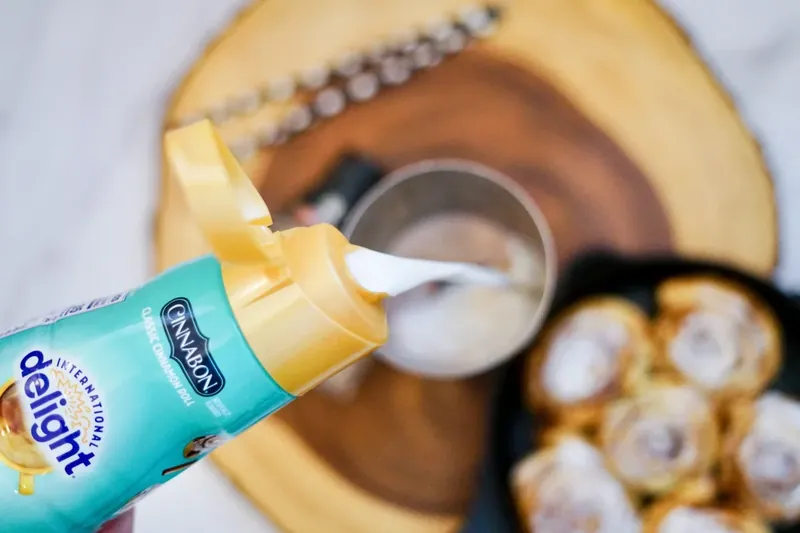 Adding cinnamon roll creamer to cocktail shaker for martini preparation