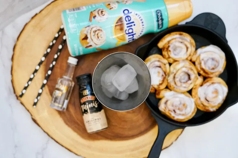 Ice cubes being added to cocktail shaker for cinnamon roll martini preparation