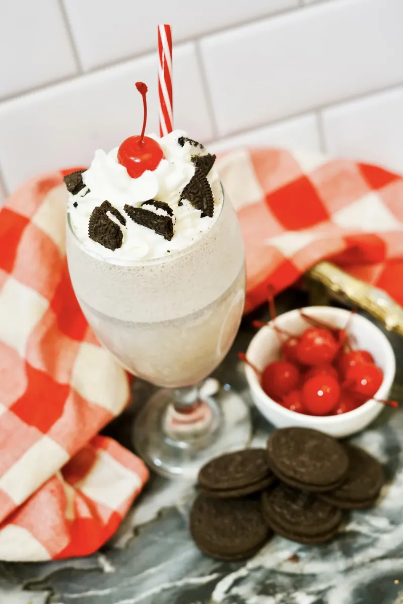 Professional looking cookies and cream milkshake with striped straw and cherry garnish