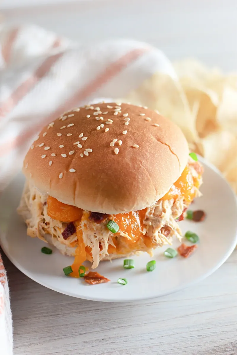 Crack chicken sandwich showing generous filling with bacon and green onions