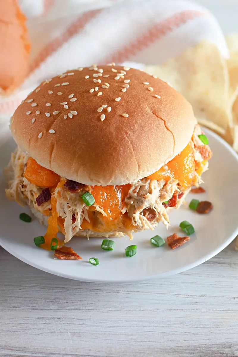 Multiple crack chicken sandwiches on plates with garnish