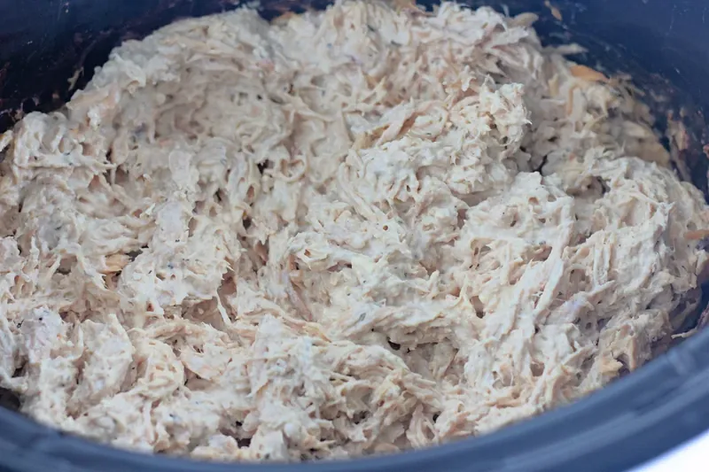 Shredded chicken mixed with cream cheese in slow cooker