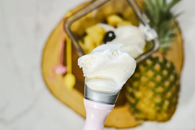Adding vanilla ice cream to blender with pineapple for Dole Whip