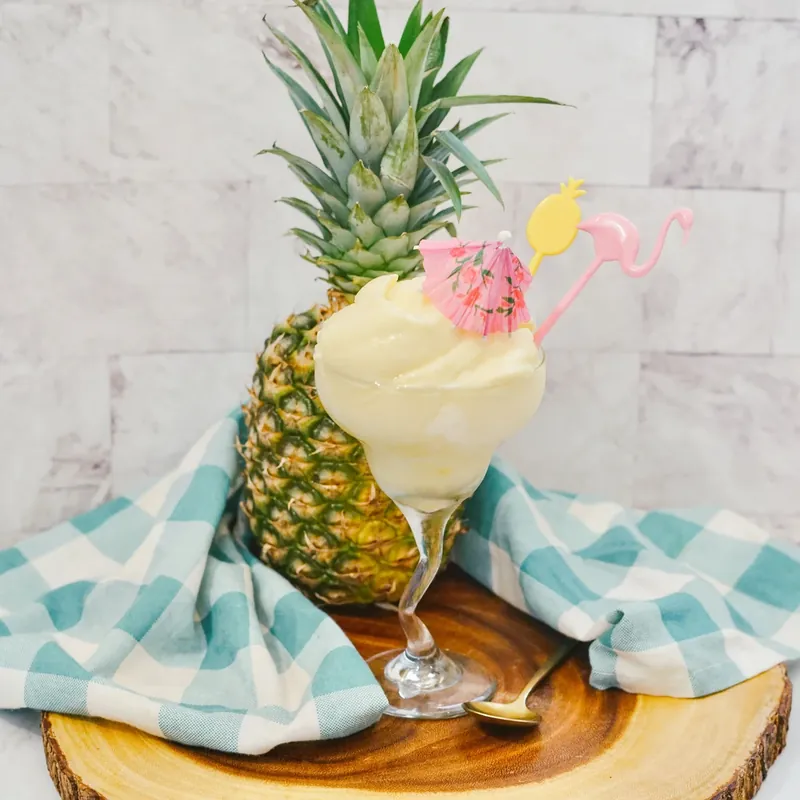 Disney Dole Whip served in glass with tropical decorations and pineapple