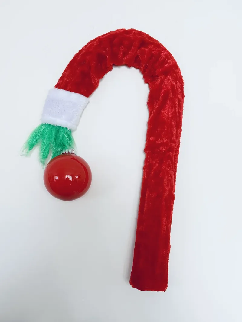 Completed DIY Grinch wreath made from Dollar Tree supplies with red velvet scarf, green fur hand, and red ornament
