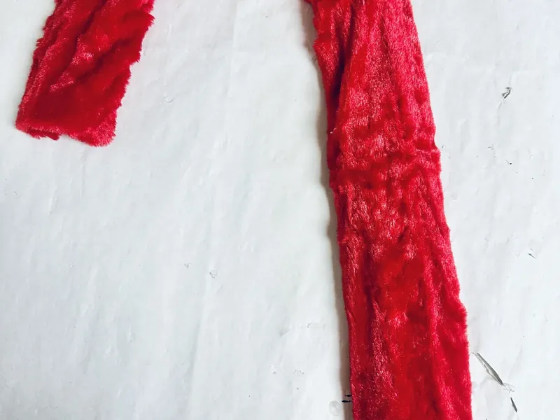 Red velvet scarf pieces being trimmed to fit candy cane wreath form