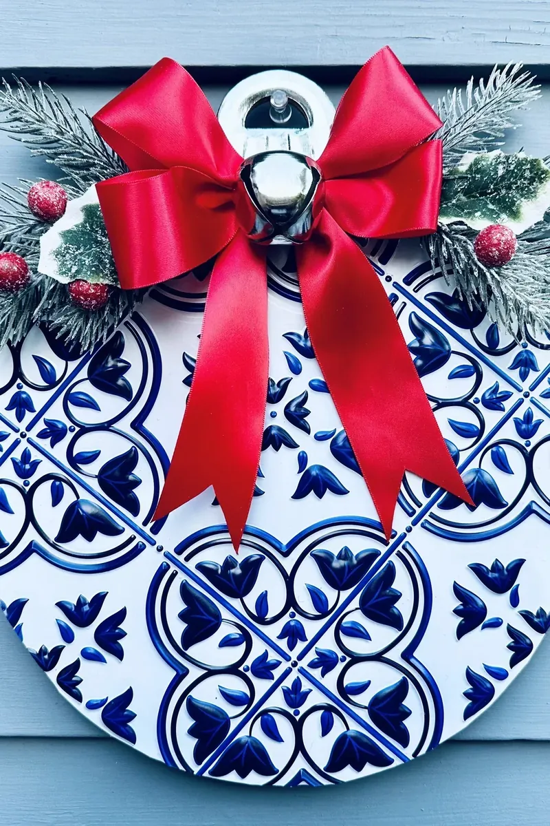 Front view of completed Dollar Tree ornament wreath with blue tile pattern and red bow