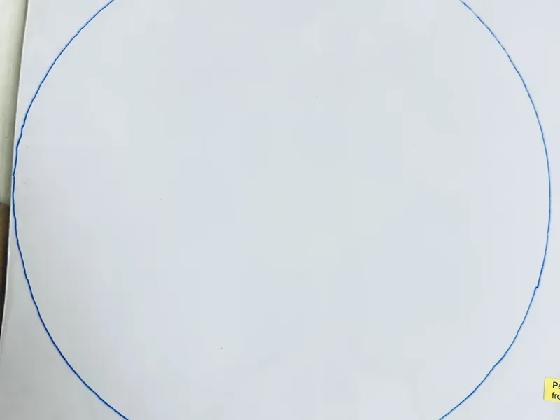 Blue marker tracing circular outline on back of white tile for Dollar Tree ornament wreath