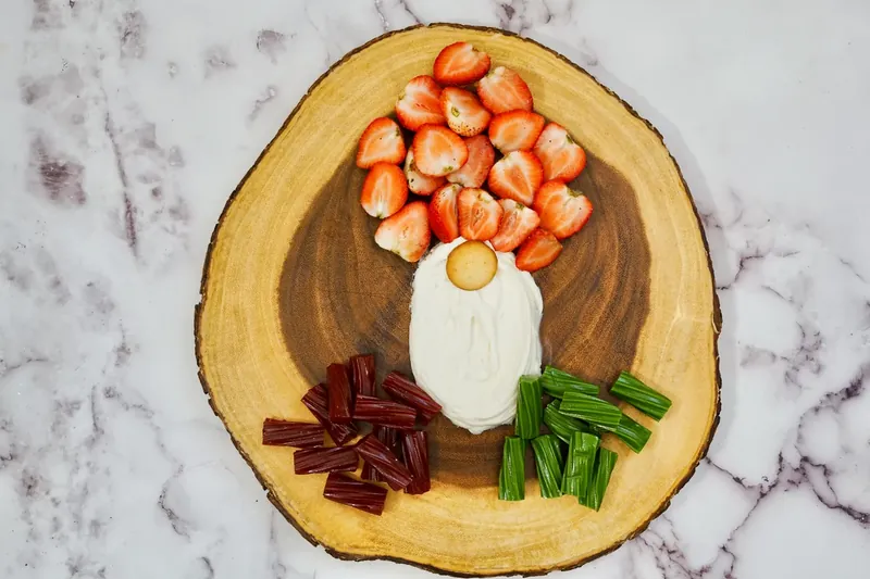 Sliced strawberries arranged above frosting beard to create gnome hat shape
