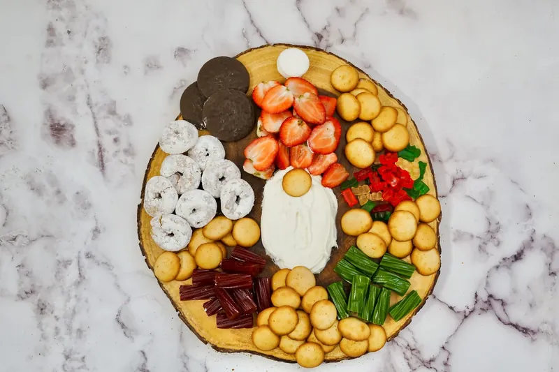 Various cookies, donuts, and colorful treats being arranged around completed gnome design