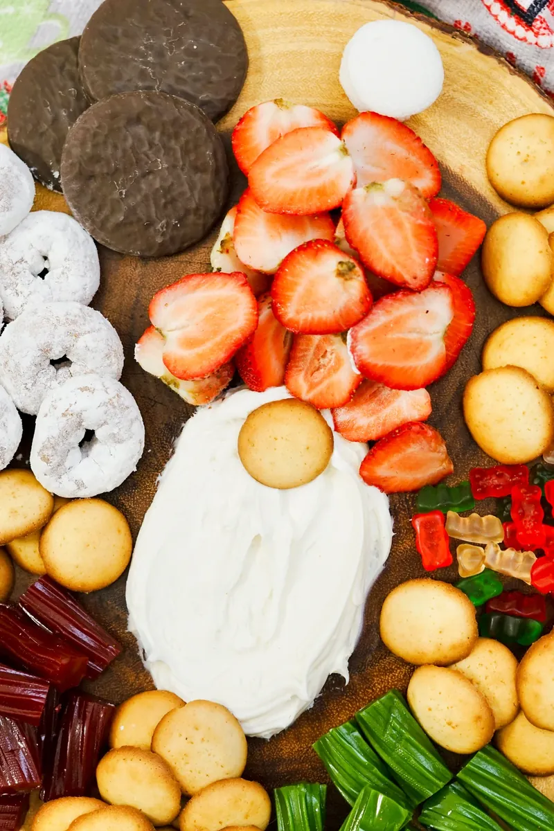 Complete gnome frosting board dessert platter with frosting beard, sliced strawberries forming hat, and colorful treats