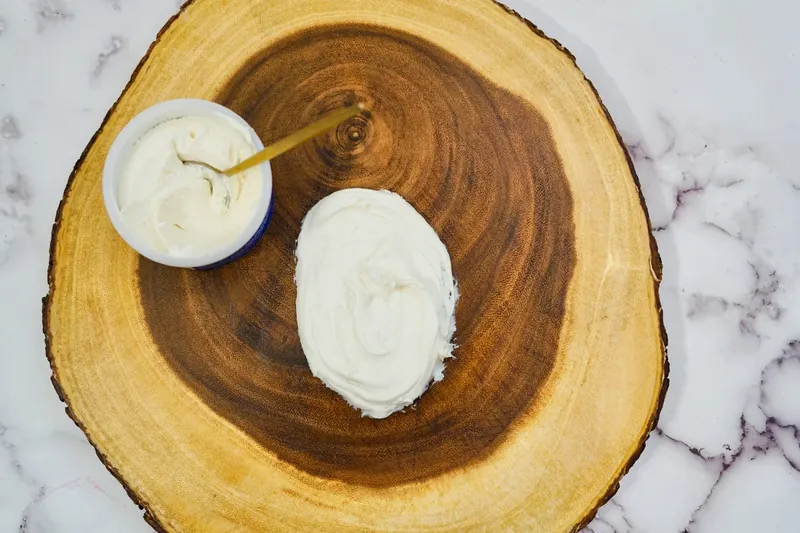 Vanilla frosting being spread on wooden platter to form gnome beard shape