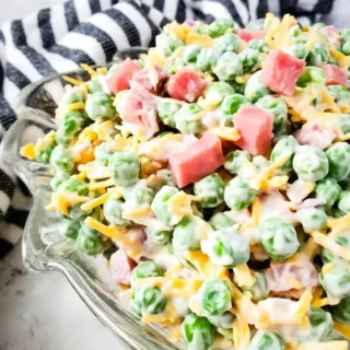 Ham and pea summer salad in decorative glass bowl with striped towel