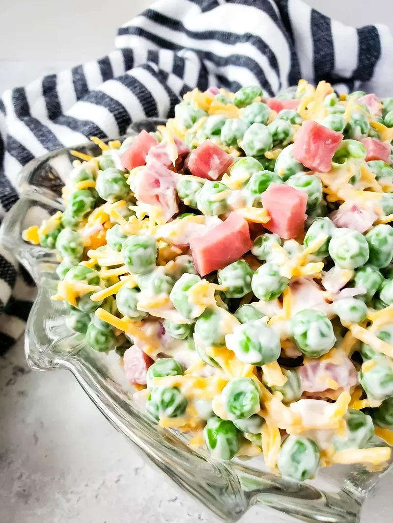 Ham and pea summer salad in decorative glass bowl with striped towel