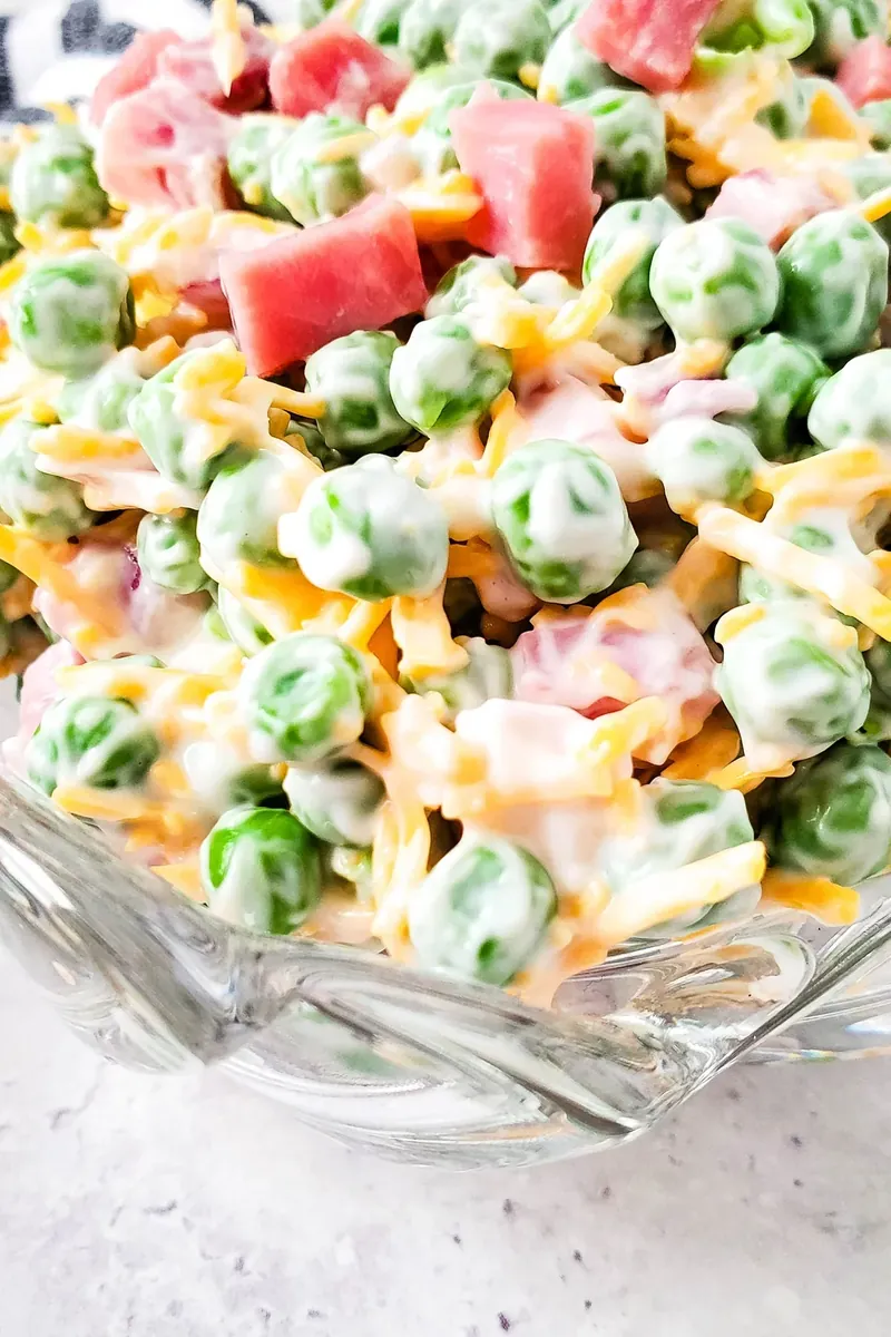 Ham and pea summer salad in glass dish showing mixed ingredients