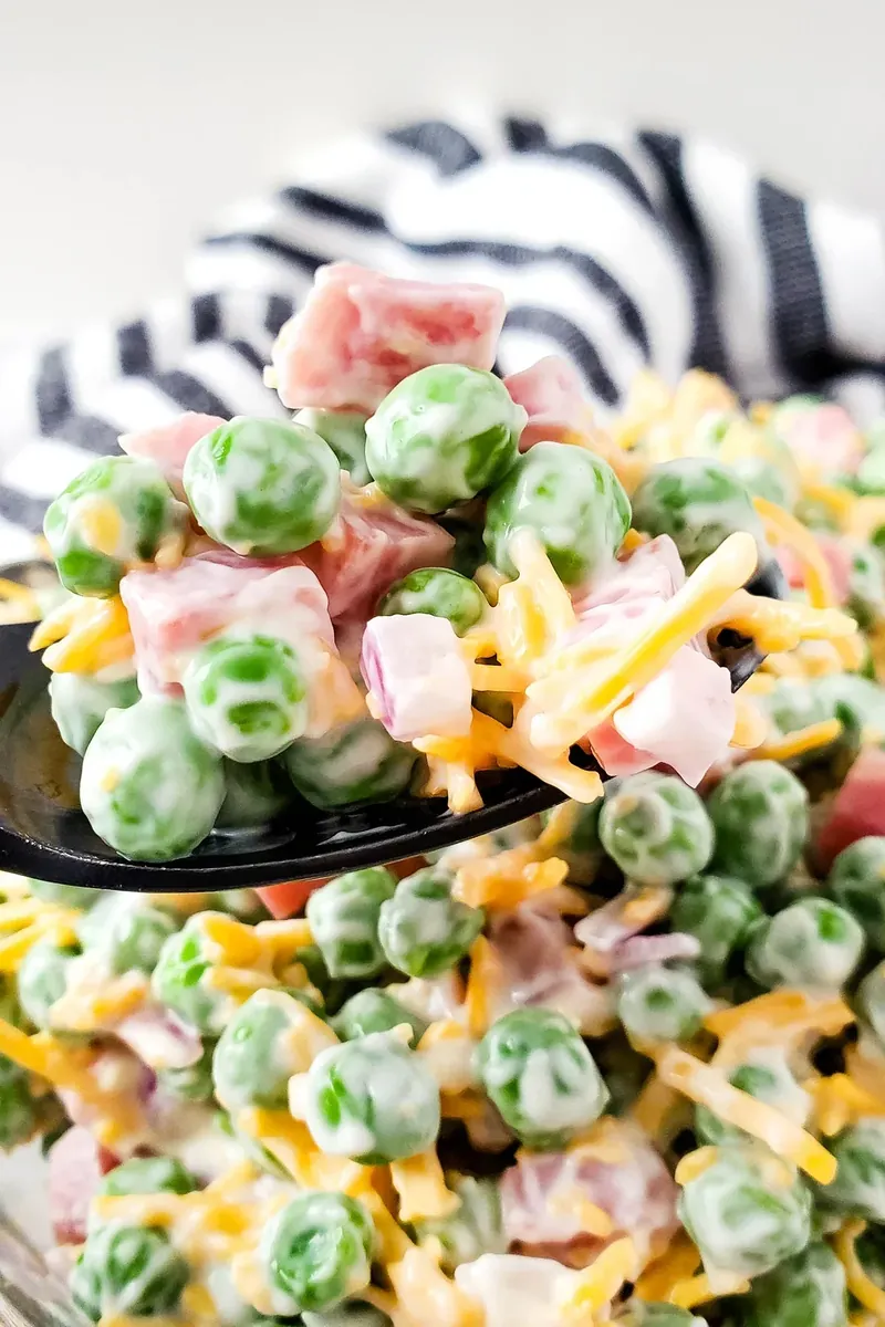 Serving spoon with ham and pea salad showing ingredients