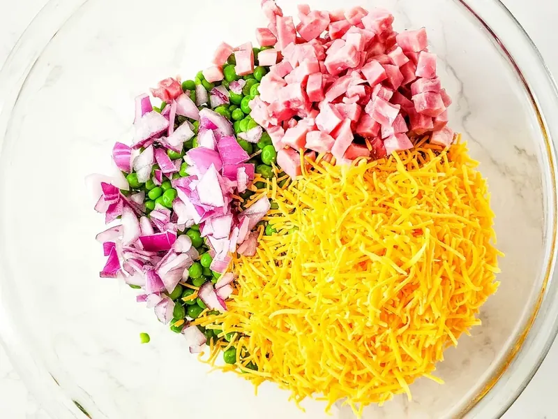 Diced red onions added to ham, peas, and cheese mixture