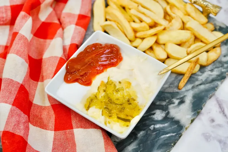 White bowl showing ketchup and pickle relish being combined with mayonnaise
