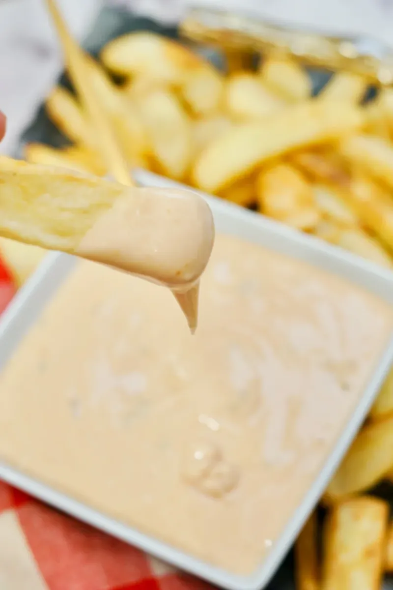 Close-up of finger dipping into creamy In-N-Out sauce showing thick consistency