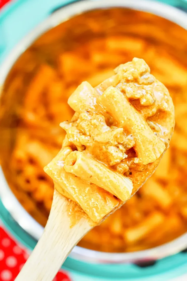 Close-up of creamy sausage rigatoni on wooden spoon showing texture