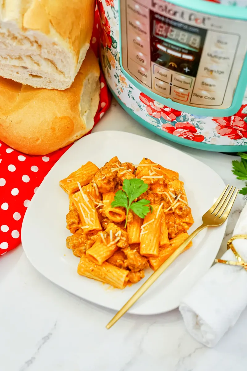 Plated creamy sausage rigatoni with bread and golden fork