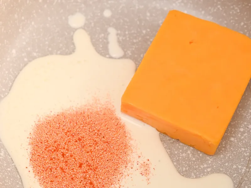Grating block cheddar cheese on cutting board