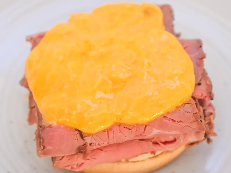 Melted cheddar cheese sauce poured over roast beef sandwich