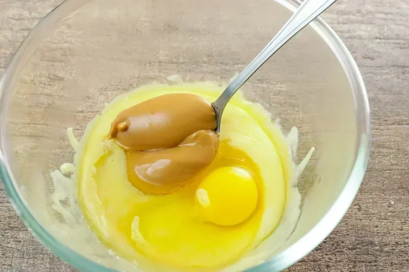 Adding egg and almond butter to melted mozzarella for keto pastry