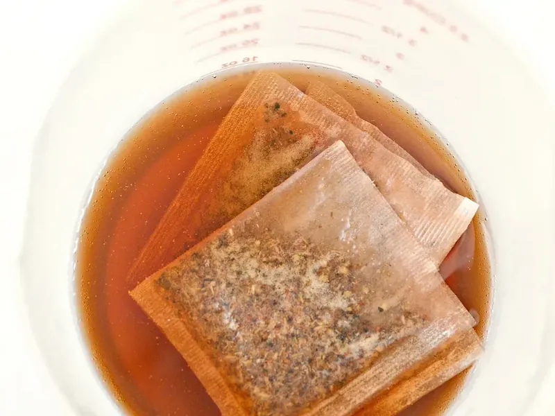 Cinnamon apple herbal tea bags steeping in hot water in white bowl