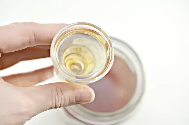 Measuring cup with gold tequila being added to tea mixture