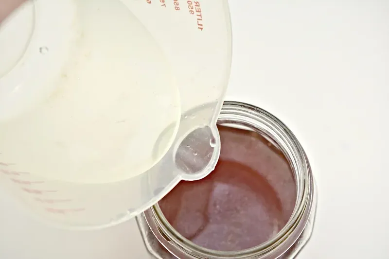 Water being poured from measuring cup into margarita mixture